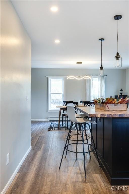 kitchen with wood counters, decorative light fixtures, a baseboard radiator, and hardwood / wood-style flooring