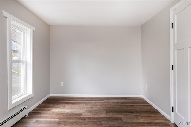 empty room with plenty of natural light, dark hardwood / wood-style floors, and baseboard heating