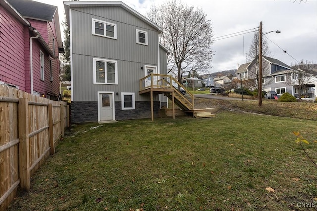 back of house featuring a wooden deck and a lawn