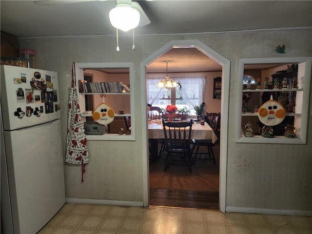 kitchen featuring white refrigerator, crown molding, and a notable chandelier