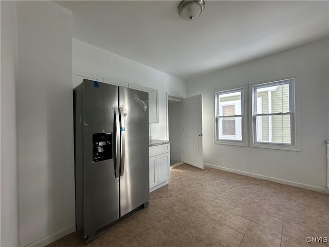 kitchen featuring white cabinetry, stainless steel fridge with ice dispenser, and light stone counters