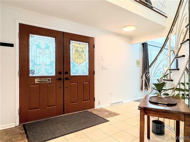 entryway with crown molding and light tile patterned floors