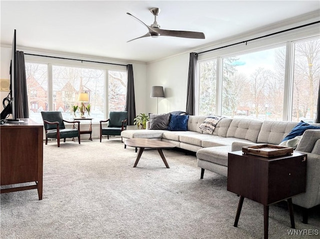 living room with ornamental molding, plenty of natural light, light colored carpet, and ceiling fan