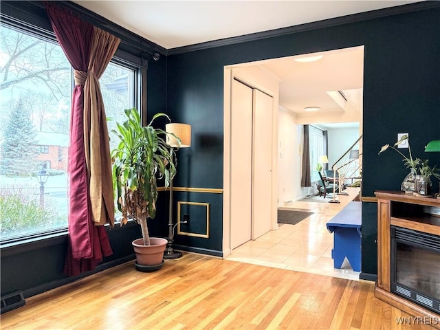 interior space featuring crown molding, plenty of natural light, and light wood-type flooring