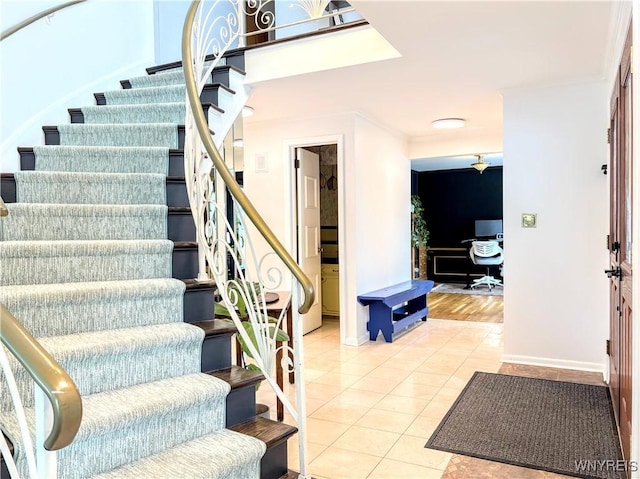 staircase with ornamental molding and tile patterned floors