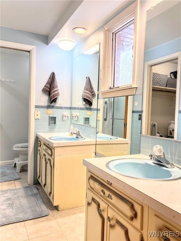 bathroom featuring tile patterned floors, toilet, tile walls, and vanity