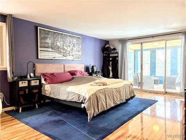 bedroom with expansive windows, hardwood / wood-style floors, and access to outside