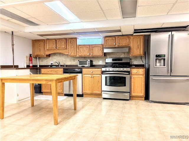 kitchen with a paneled ceiling, appliances with stainless steel finishes, sink, and backsplash