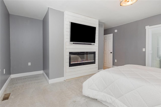 bedroom with a large fireplace and light carpet