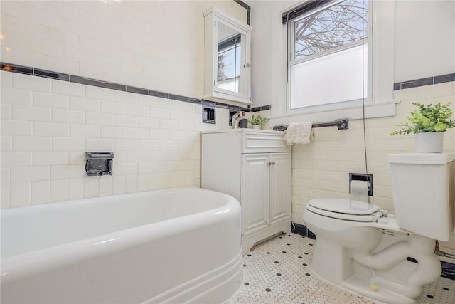 bathroom with a tub to relax in, toilet, tile patterned flooring, and tile walls