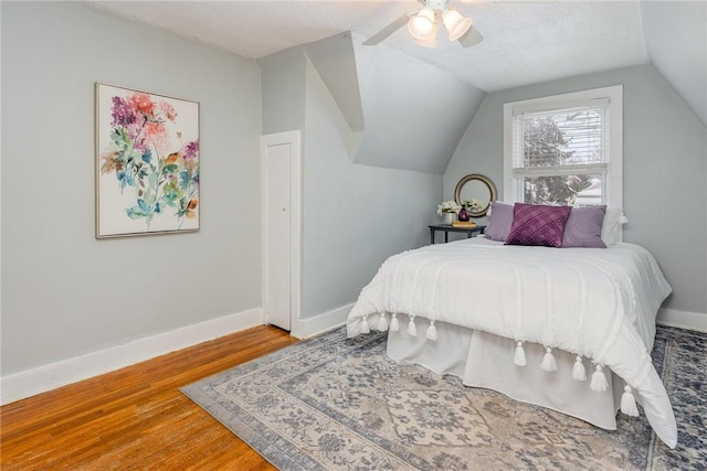 bedroom with ceiling fan, lofted ceiling, hardwood / wood-style floors, and a textured ceiling