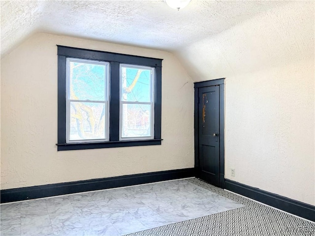 bonus room with lofted ceiling and a textured ceiling