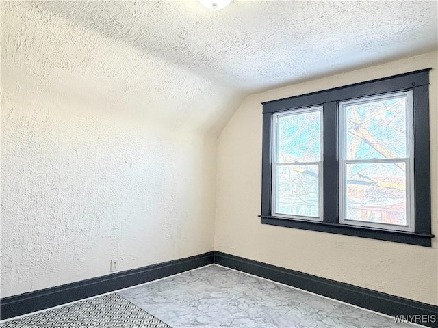 bonus room featuring lofted ceiling and a textured ceiling