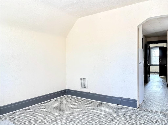 carpeted empty room featuring lofted ceiling and a textured ceiling