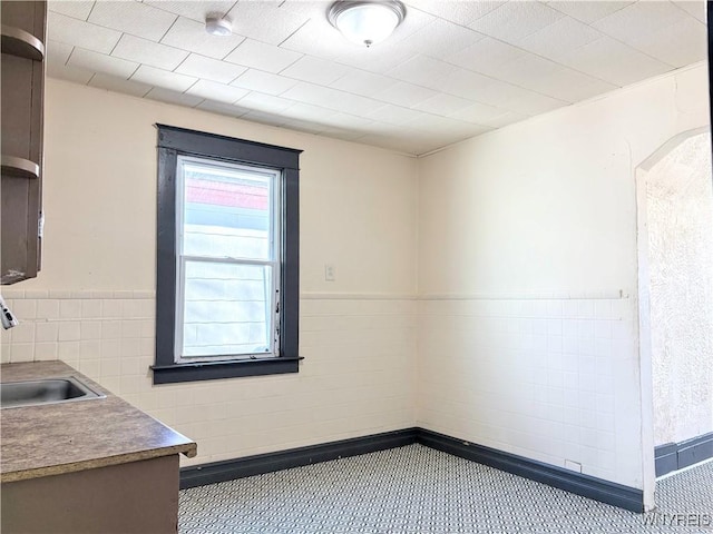 spare room featuring sink and tile walls