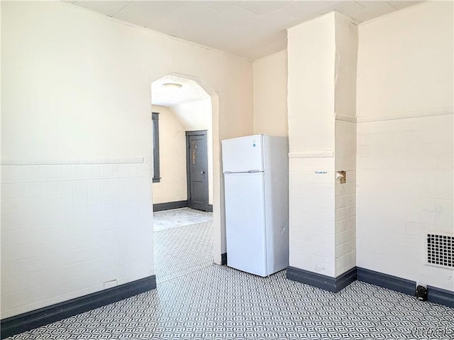 interior space with lofted ceiling and tile walls