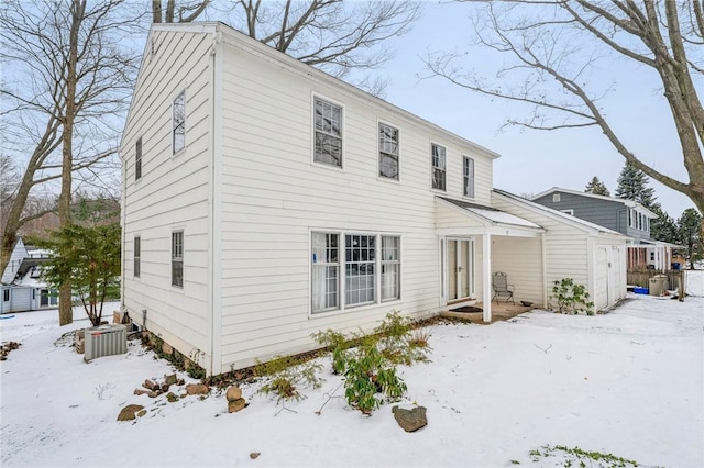 snow covered back of property featuring central AC unit