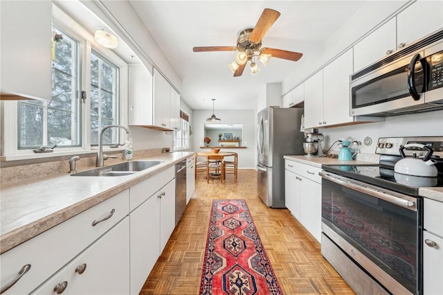 kitchen with white cabinetry, appliances with stainless steel finishes, sink, and decorative light fixtures