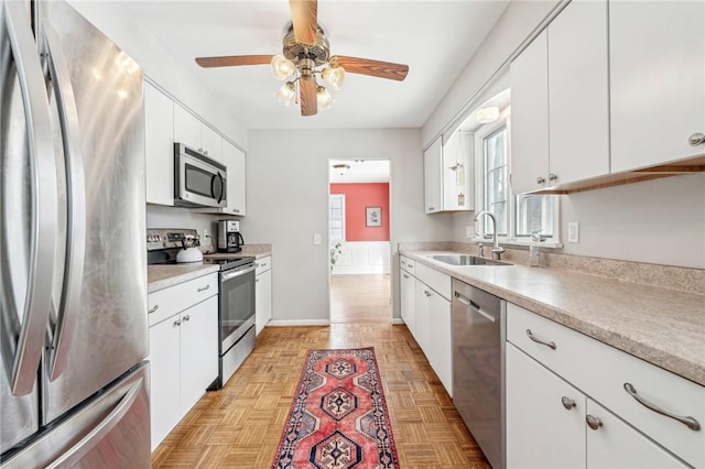 kitchen featuring appliances with stainless steel finishes, sink, light parquet floors, and white cabinets