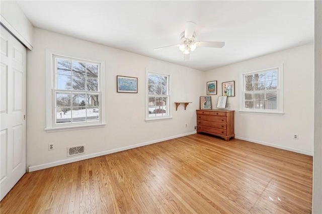 unfurnished bedroom featuring ceiling fan, multiple windows, and light wood-type flooring