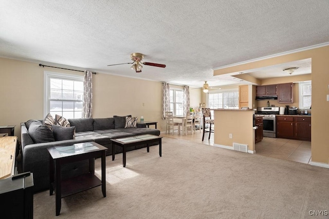 living room with ornamental molding, light carpet, ceiling fan, and a textured ceiling