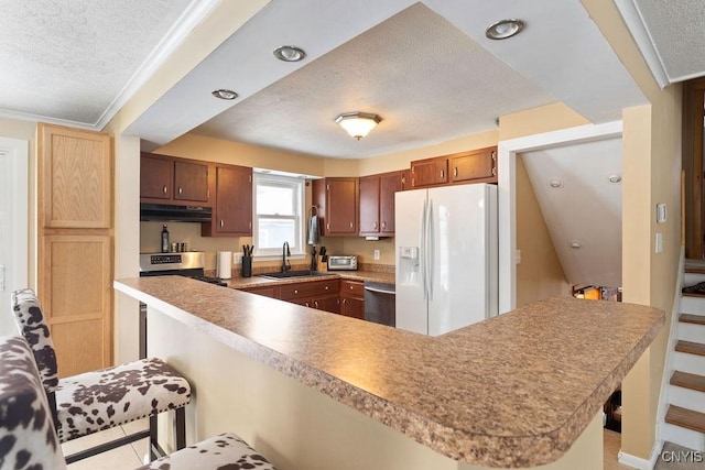 kitchen with a breakfast bar, sink, kitchen peninsula, stainless steel appliances, and a textured ceiling