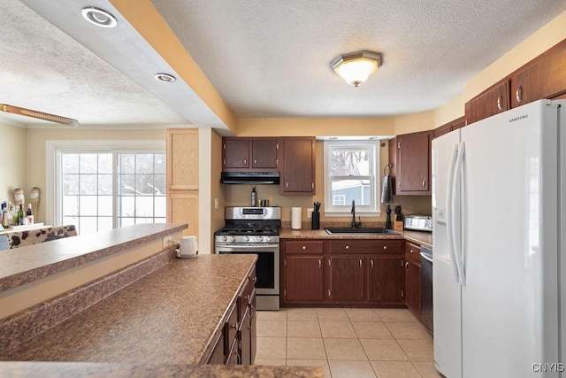 kitchen featuring stainless steel appliances, sink, a textured ceiling, and light tile patterned floors