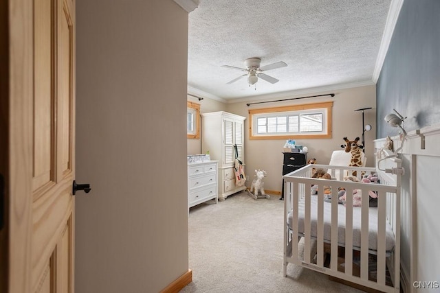 carpeted bedroom featuring ceiling fan, ornamental molding, a nursery area, and a textured ceiling