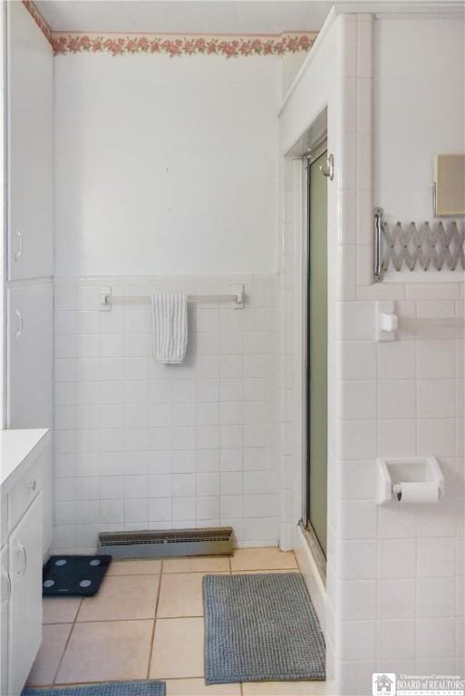 bathroom featuring tile patterned floors, vanity, an enclosed shower, and tile walls