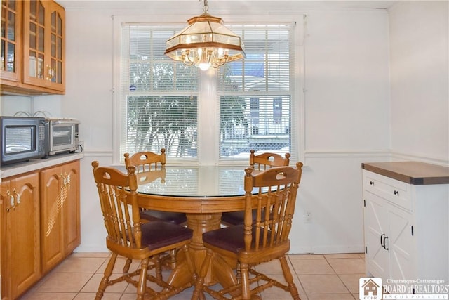 tiled dining space featuring a healthy amount of sunlight and an inviting chandelier