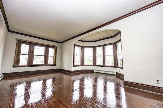 spare room with ornamental molding, wood-type flooring, a wealth of natural light, and a baseboard heating unit