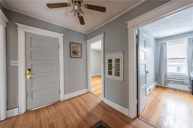 foyer entrance with ceiling fan, light hardwood / wood-style flooring, ornamental molding, and a textured ceiling