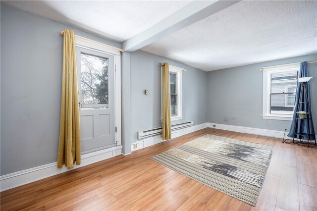 interior space featuring wood-type flooring, a baseboard heating unit, and a textured ceiling