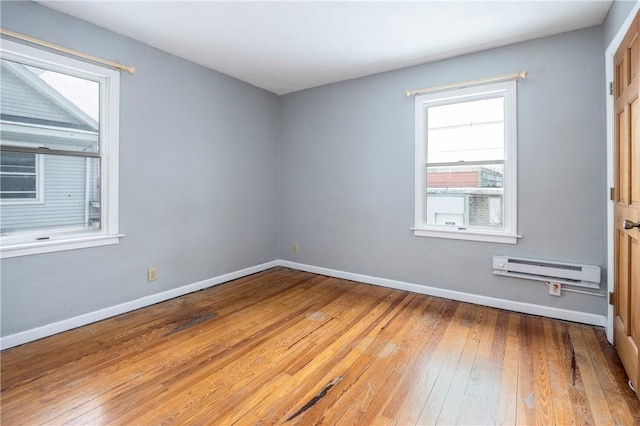 empty room featuring wood-type flooring and a baseboard radiator