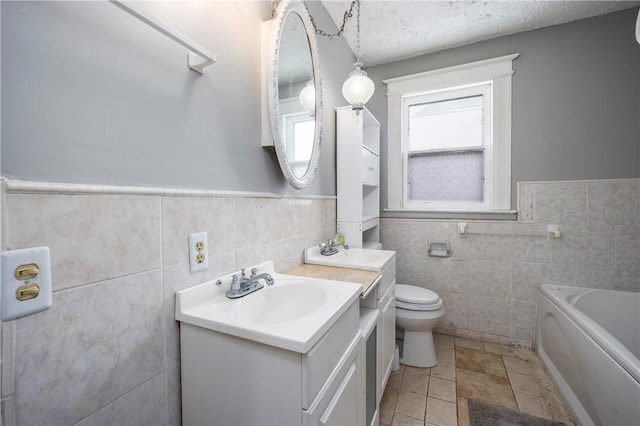 bathroom with a bathing tub, tile walls, vanity, toilet, and a textured ceiling