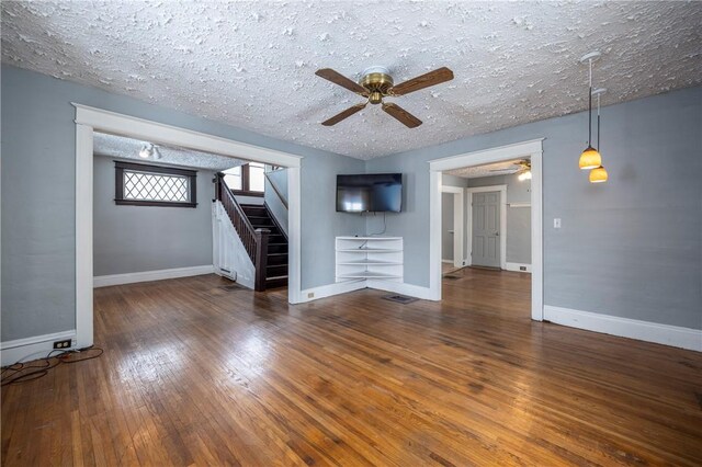 unfurnished living room with ceiling fan, dark wood-type flooring, and a textured ceiling