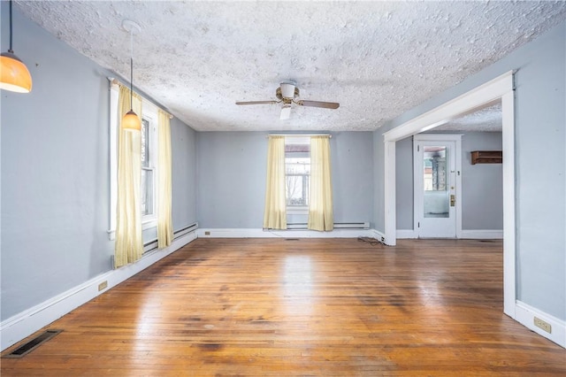 empty room with dark hardwood / wood-style flooring, ceiling fan, a baseboard radiator, and a textured ceiling