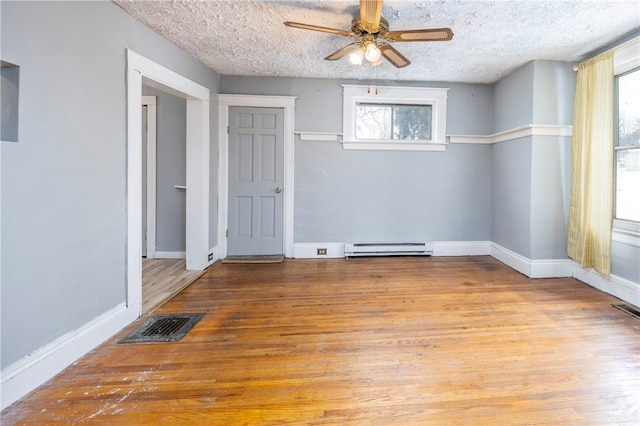 spare room featuring ceiling fan, a baseboard radiator, a textured ceiling, and light wood-type flooring