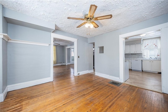 interior space with ceiling fan, light hardwood / wood-style flooring, sink, and a textured ceiling