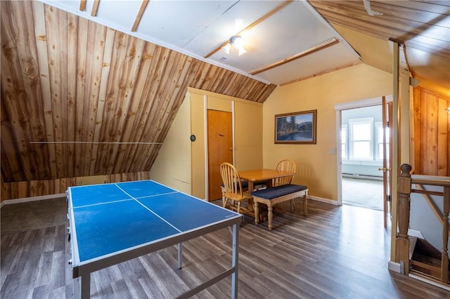 recreation room featuring dark wood-type flooring, a baseboard radiator, vaulted ceiling, and wood walls