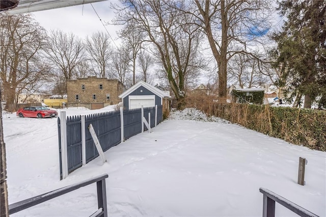 yard layered in snow with a garage and an outdoor structure