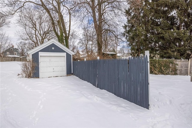 snowy yard with a garage and an outdoor structure