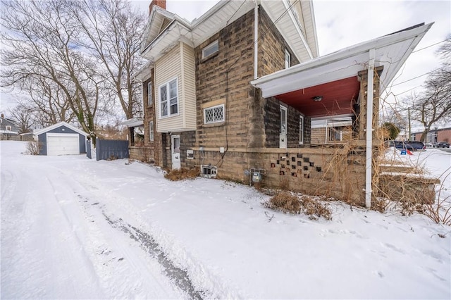 view of snowy exterior with an outbuilding and a garage