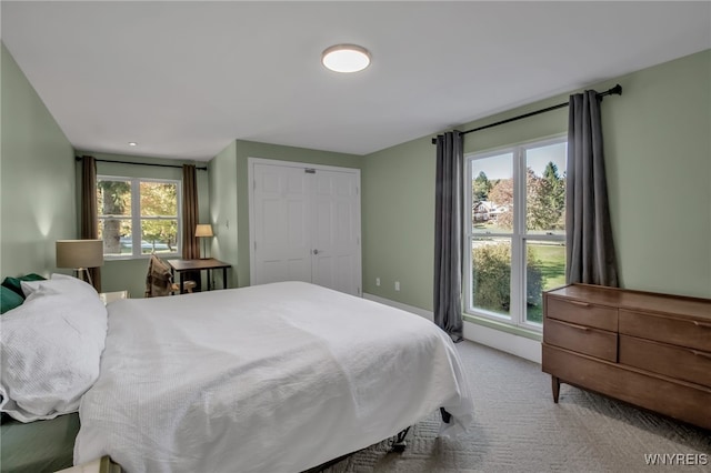 carpeted bedroom featuring multiple windows and a closet