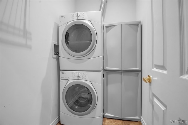 clothes washing area featuring cabinets and stacked washer / dryer