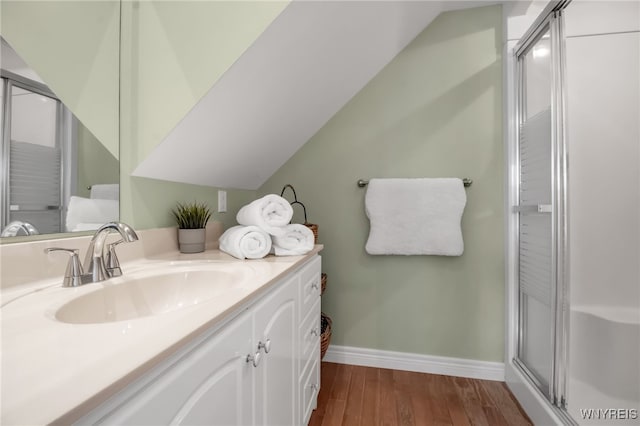 bathroom featuring hardwood / wood-style flooring, lofted ceiling, vanity, and a shower with door