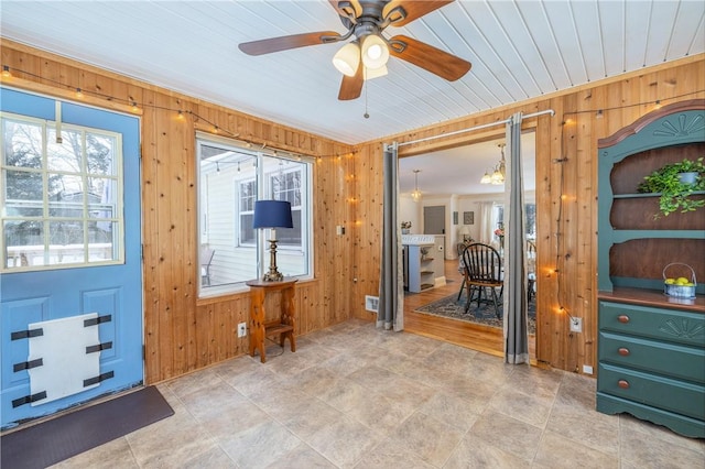 doorway featuring ceiling fan and wood walls