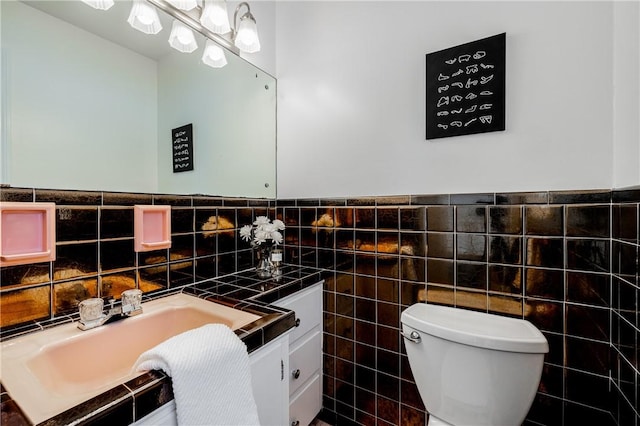 bathroom featuring vanity, toilet, and tile walls