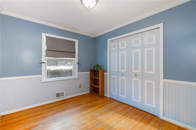 unfurnished bedroom with ornamental molding, a closet, and light wood-type flooring