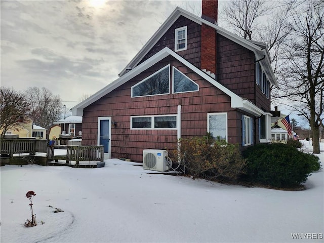 snow covered rear of property with ac unit